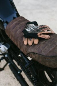 Leather gloves resting on a classic motorcycle seat in an outdoor setting, embodying adventure.
